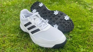The Adidas Tech Response 2.0 golf shoes in a white and black colorway showing off their spiked sole design