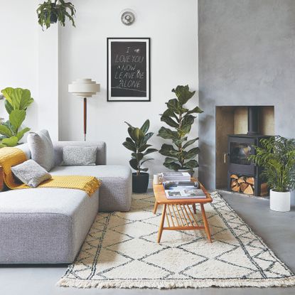 A living room with a modern grey low sofa, a Berber-style rug and a retro coffee table