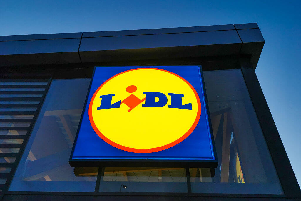 The Lidl logo on the outside of a Lidl store in dusk lighting.