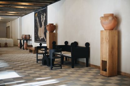 Entrance hall of Hotel Kokhta with rustic decor and furniture, clay pots and art on the wall 