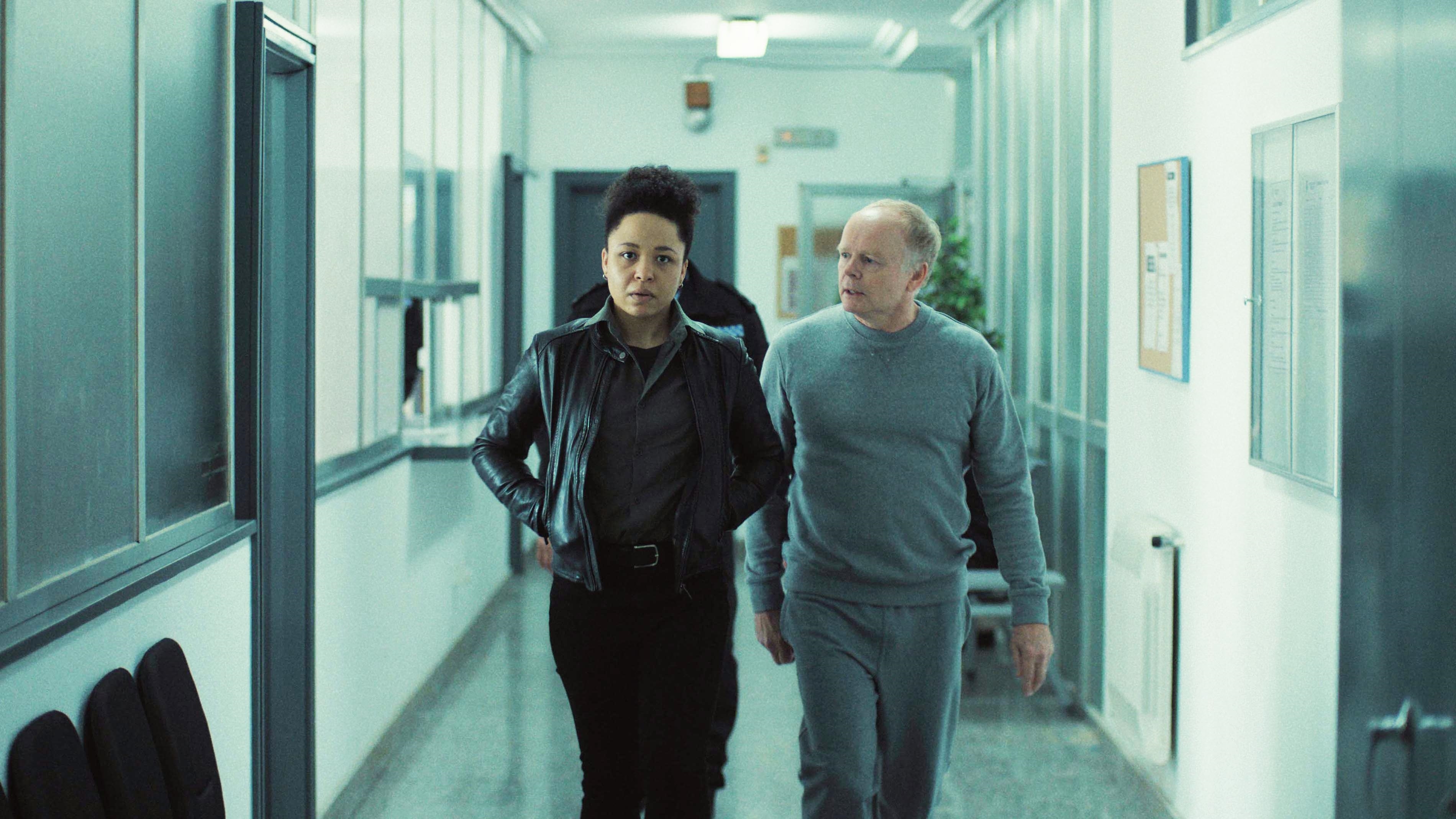 Huw and Jenny talk in the police station - Huw is in his grey prison tracksuit