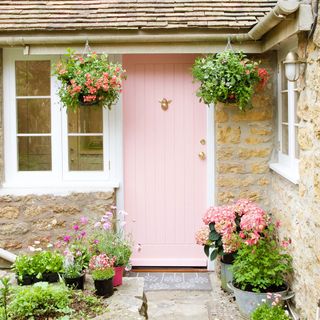 pink front door with door mat and flowers