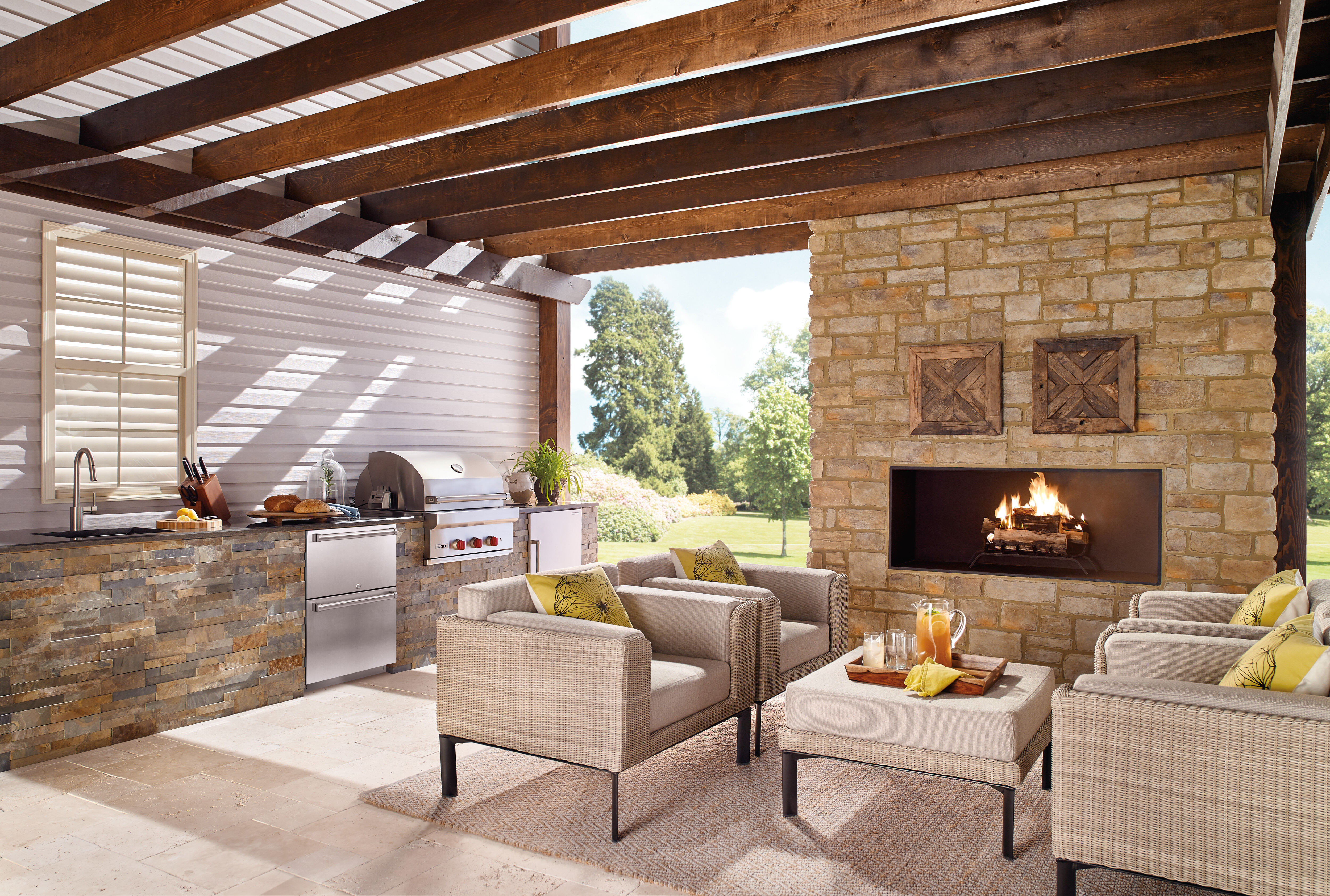 An outdoor space with a seating area, a fireplace, and a built in grill, sink and fridge