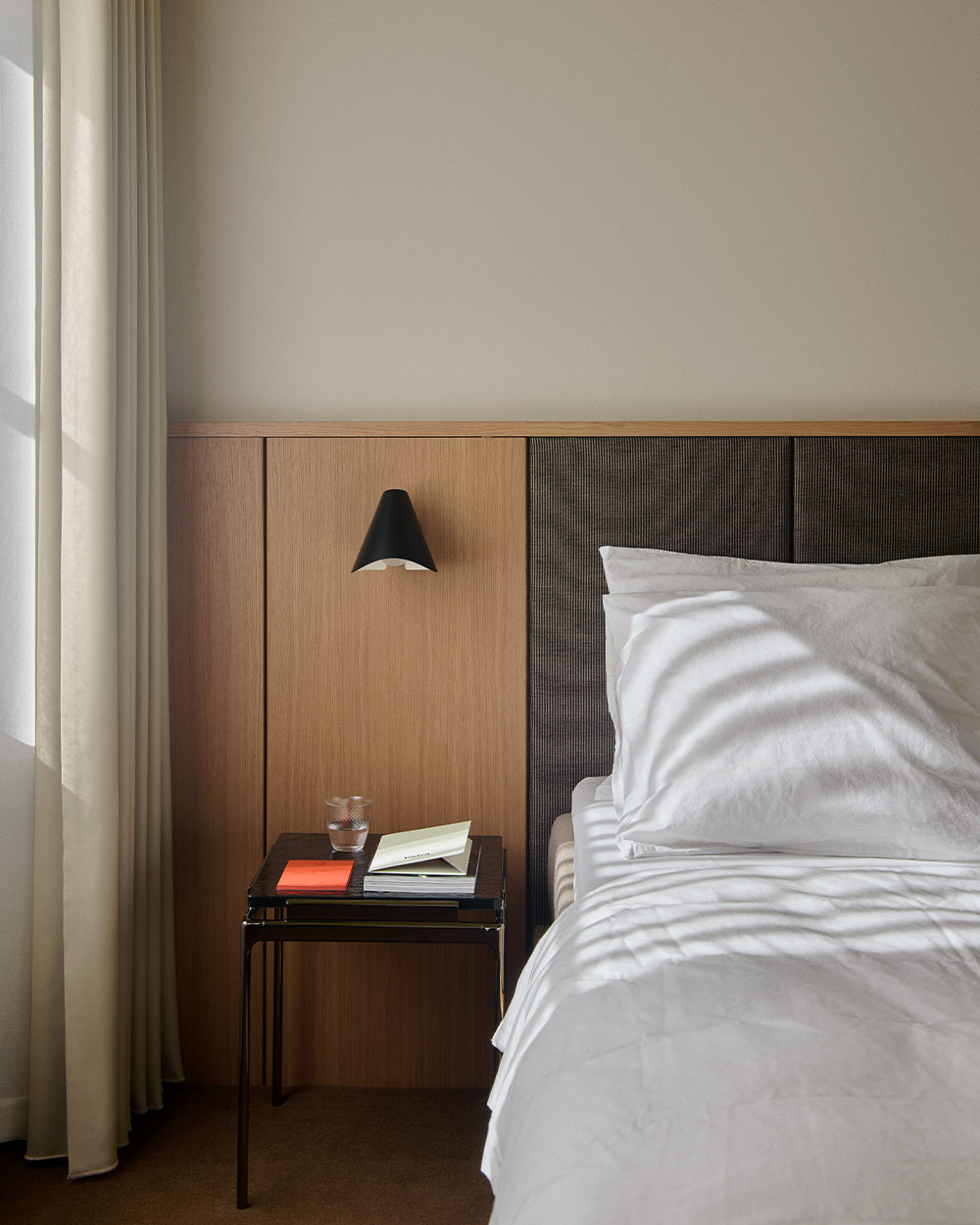 a hotel bedroom with a wooden headboard and white bed linen