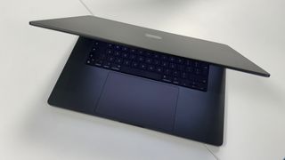 A semi-closed MacBook on a white table top.