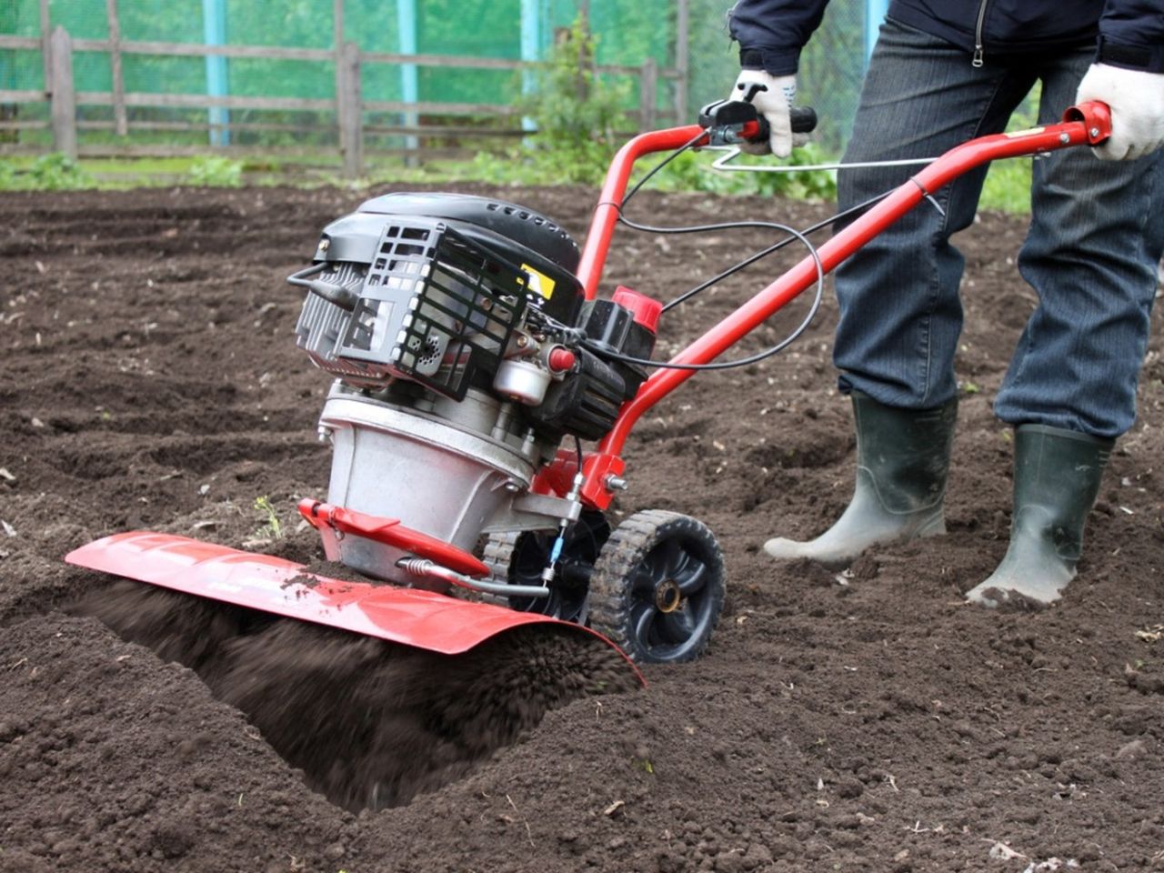 Person Tilling Soil In A Garden