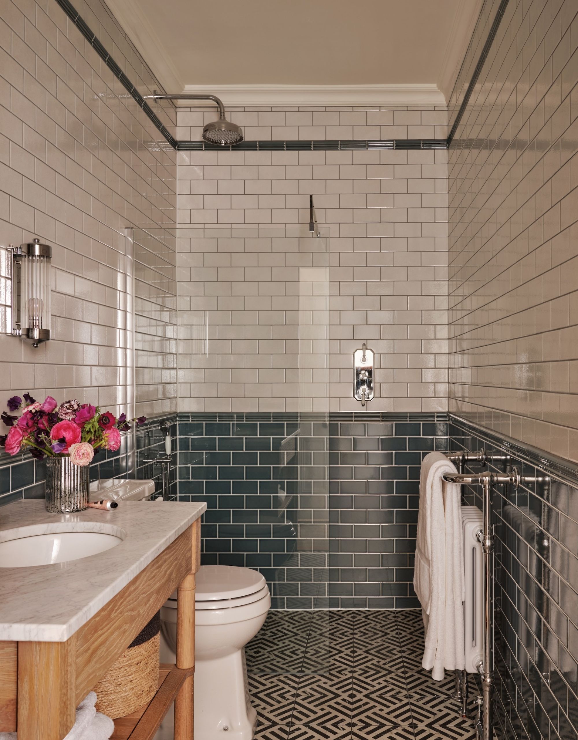 A small tiled bathroom with a shower at one end, shown with green Metro tiles half way up the walls, then white tiles to the ceiling plus a wooden vanity basin and geometric floor tiles