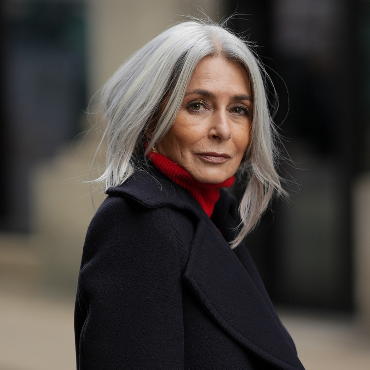 best eyeliner for mature skin Regina Burton is seen wearing a double-breasted navy blue wool coat with gold buttons from Zara; a bright red turtleneck sweater from Victoria Beckham; her silver-grey hair is styled straight and worn loose with a center parting on October 16, 2025 in Hamburg