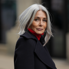 best eyeliner for mature skin Regina Burton is seen wearing a double-breasted navy blue wool coat with gold buttons from Zara; a bright red turtleneck sweater from Victoria Beckham; her silver-grey hair is styled straight and worn loose with a center parting on October 16, 2025 in Hamburg