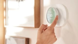 Woman's hand adjusting Google Nest Thermostat 2020