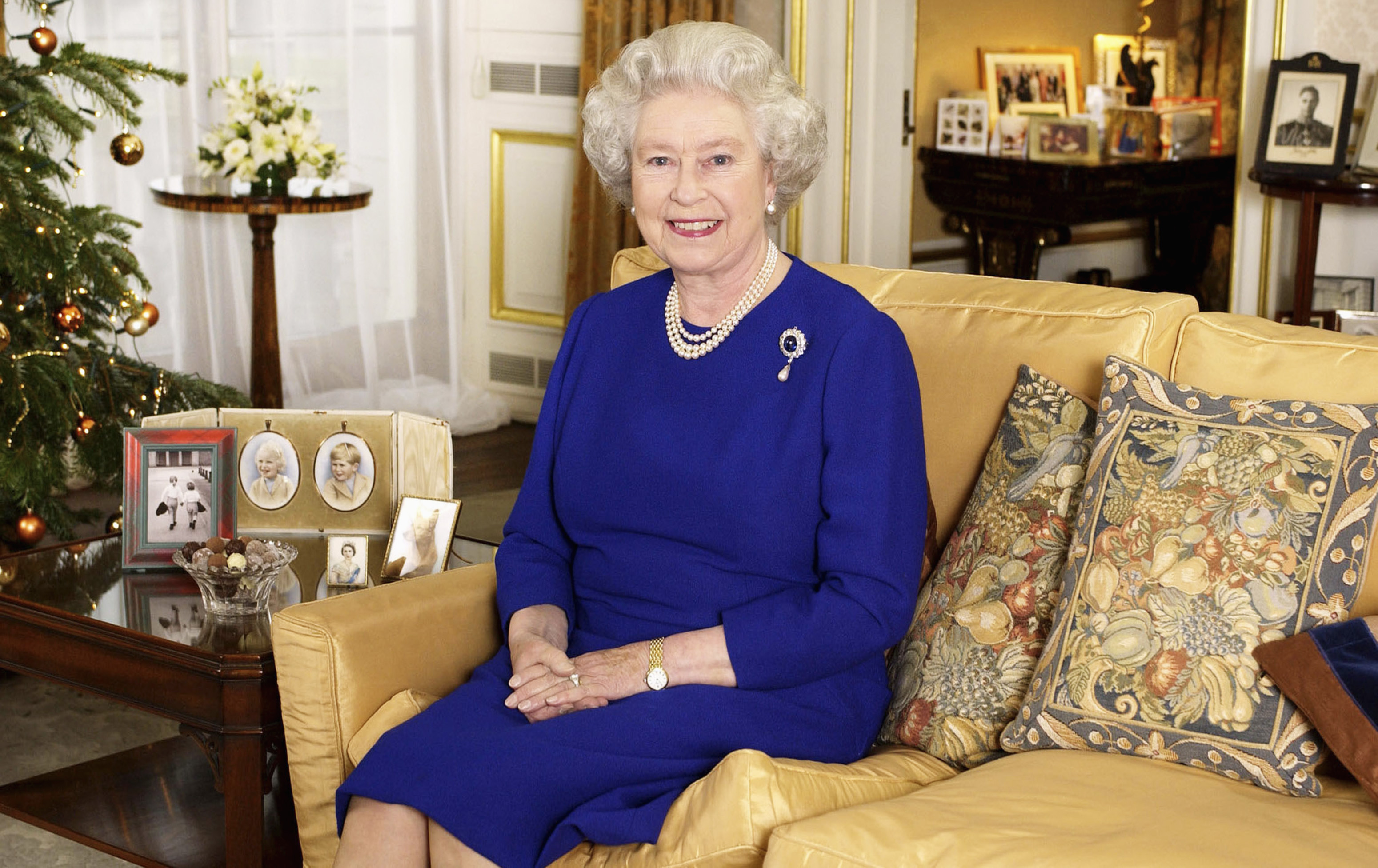 Queen Elizabeth wearing a blue dress sitting on a sofa
