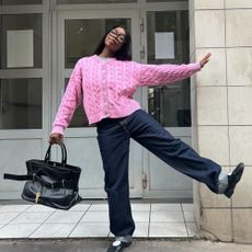Influencer @aude_julie wears a pink knitted cardigan within indigo jeans and Nike Air Rift trainers.