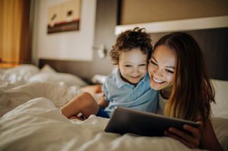 Mother and young son in bed using tablet
