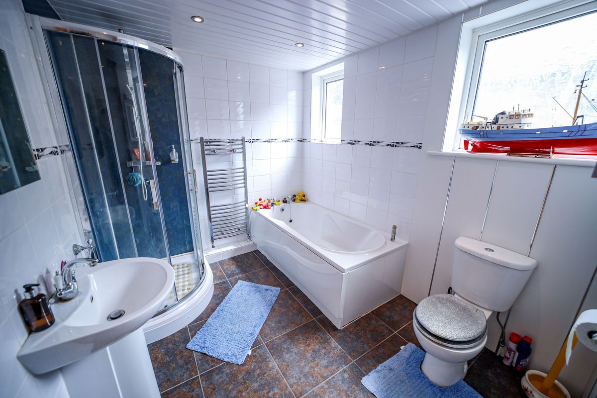 A white tiled bathroom with bath and walk-in shower