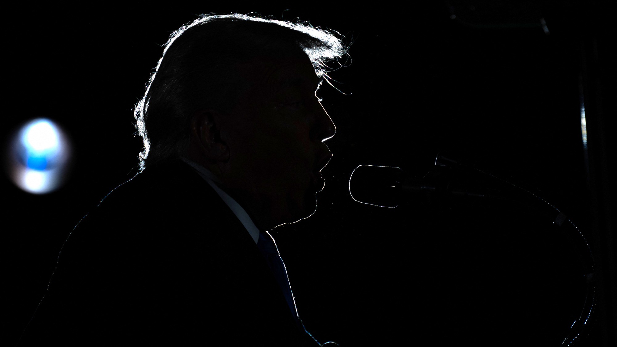 Donald Trump, seen in silhouette, delivers commencement remarks at the University of Alabama in Tuscaloosa