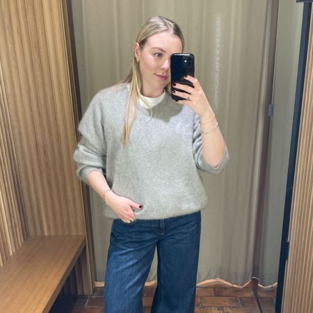 Woman wears grey sweater, blue jeans