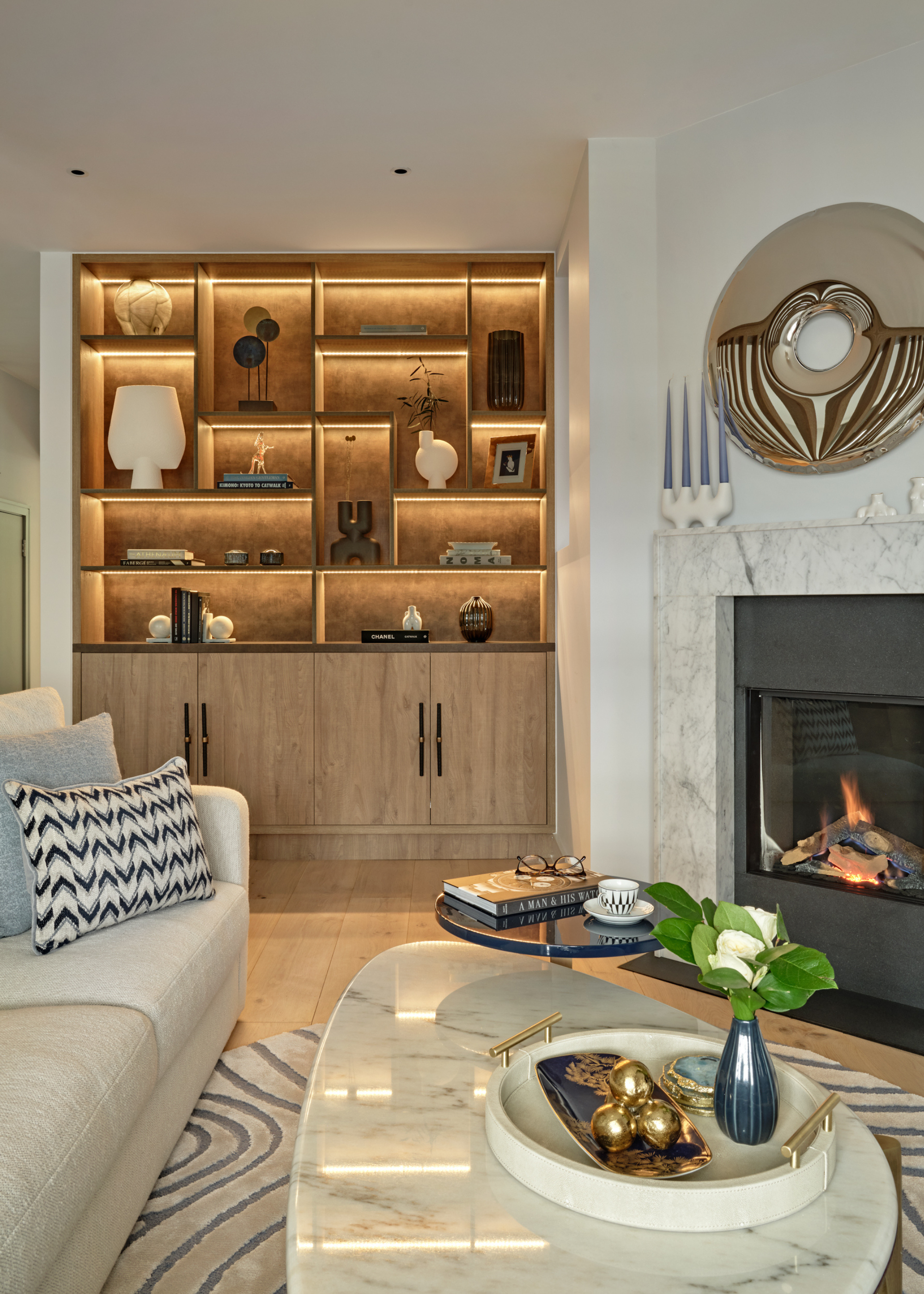 a living room with backlit recessed cabinetry and a fireplace