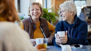 Women talking over table with cup of tea after learning about how to support someone with depression