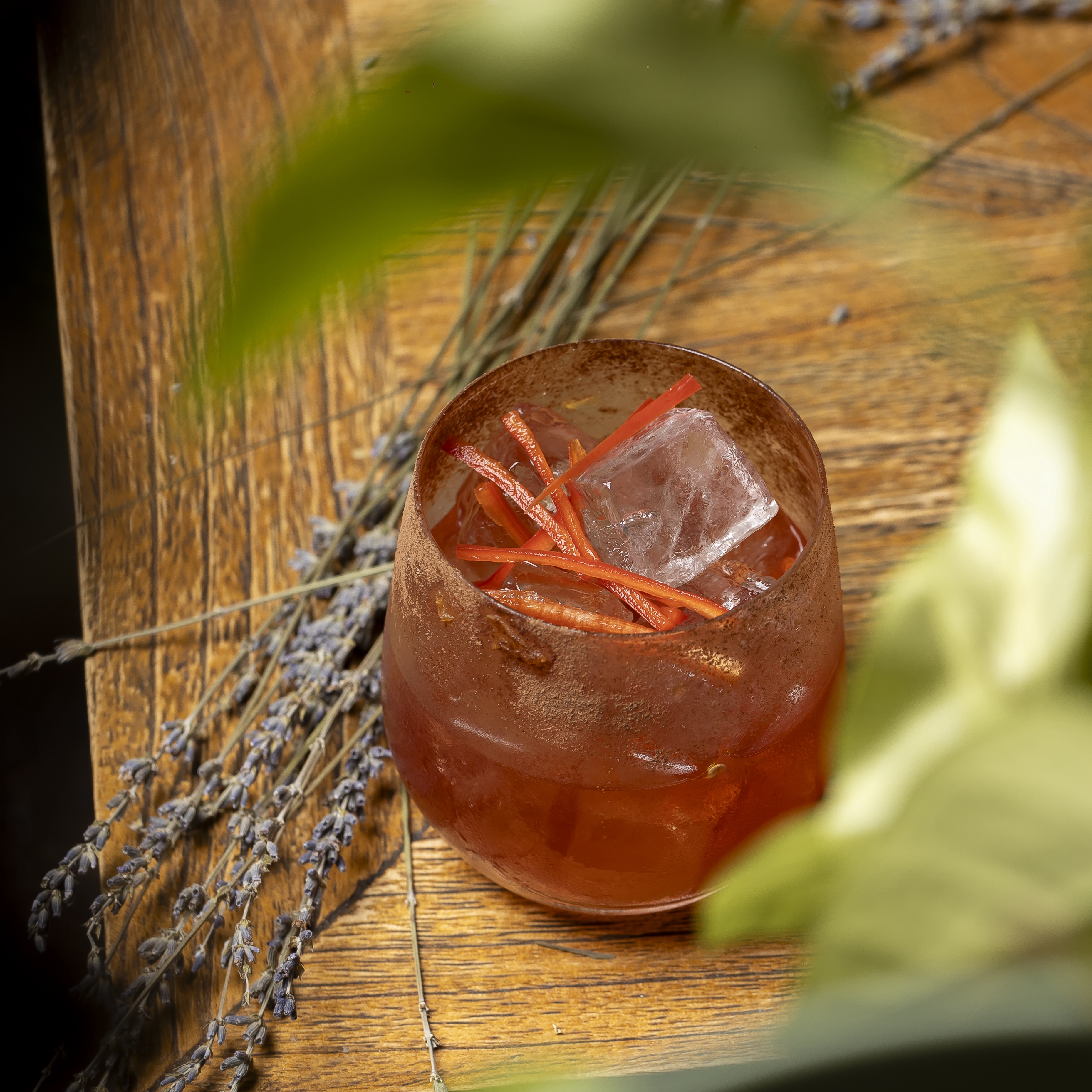an image of a negroni cocktail on a brown rustic table with some lavender decoration