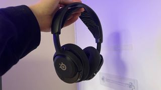 SteelSeries Arctis Nova 5 Wireless gaming headset held by reviewer against a white wall