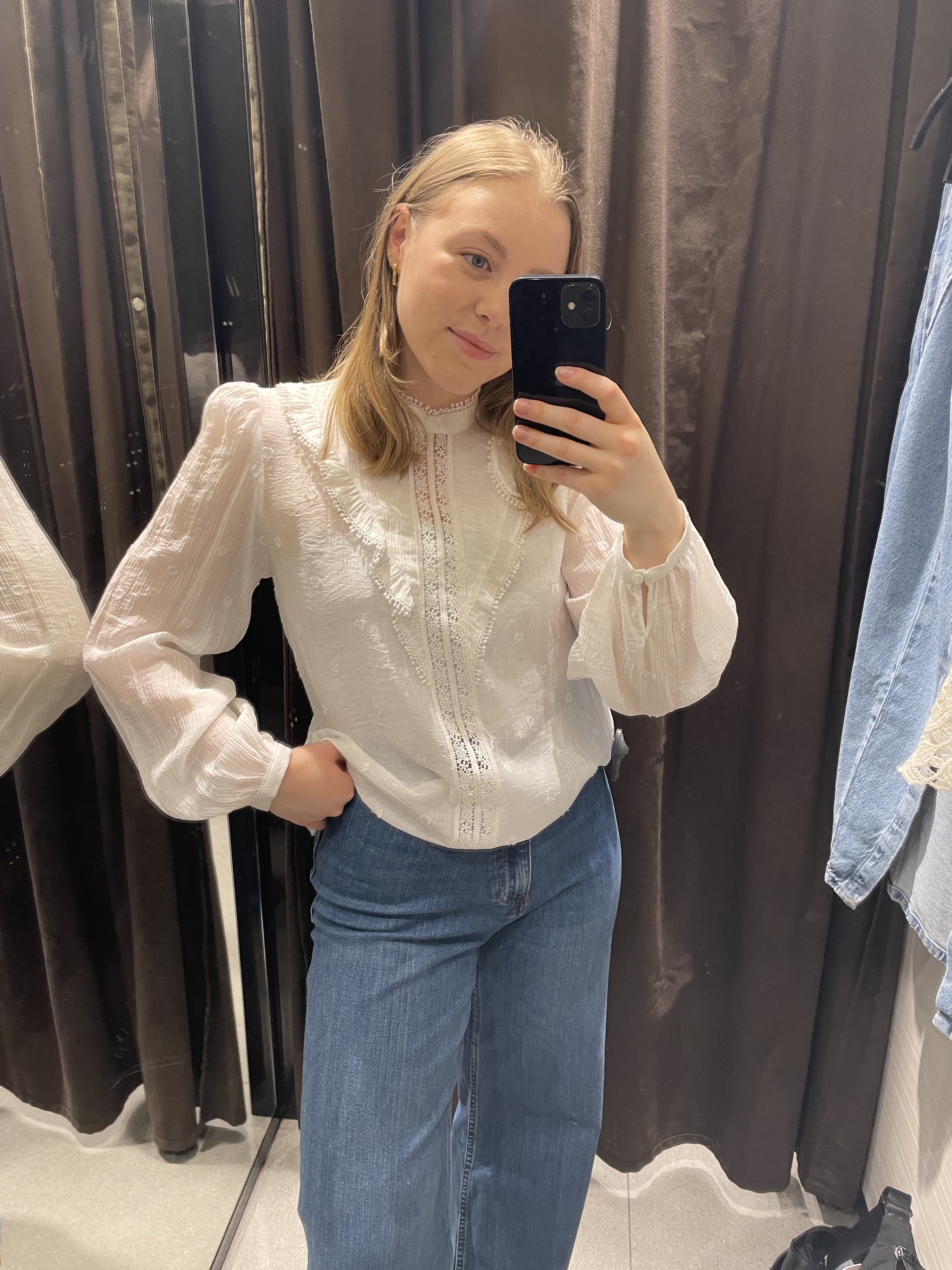 Woman in dressing room wears lace trim top and blue jeans