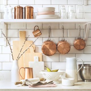 A white kitchen with hanging copper pots