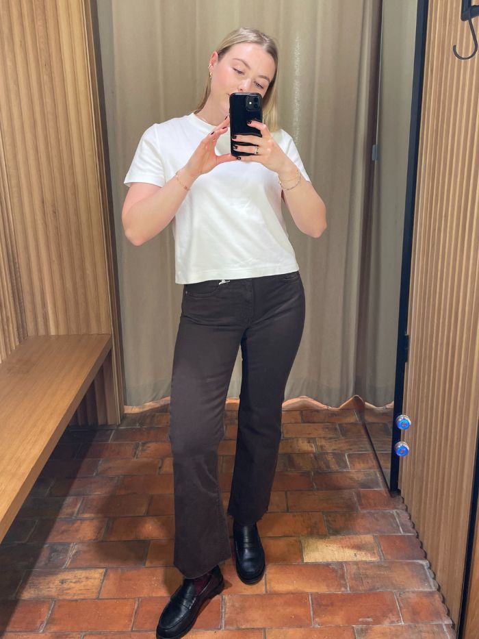 Woman wears white t-shirt and brown flare jeans