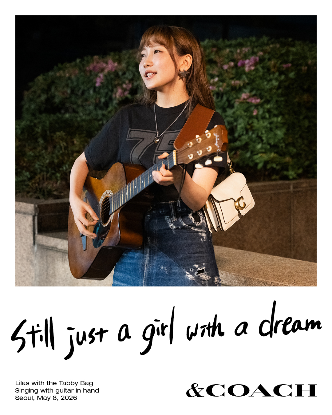 Lilas wearing a black T-shirt and denim skirt with a wooden guitar in her hand, adn a white Coach Tabby bag
