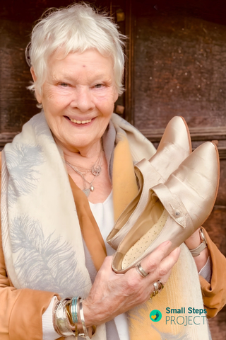 Dame Judi Dench holding her shoes ahead of the auction.