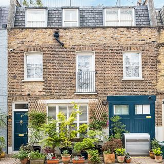 row house exterior with stone wall white windows and plants