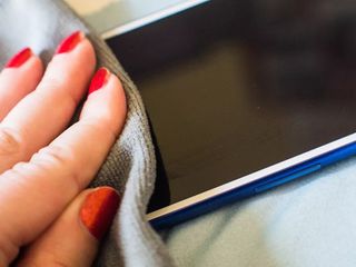 A hand cleaning a phone with a microfiber cloth