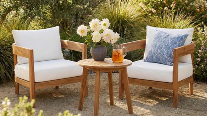 two outdoor chairs with white cushions and a small table 