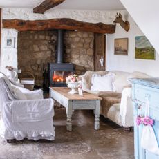 cottage living room with log burner, white walls, vintage furniture and original beams