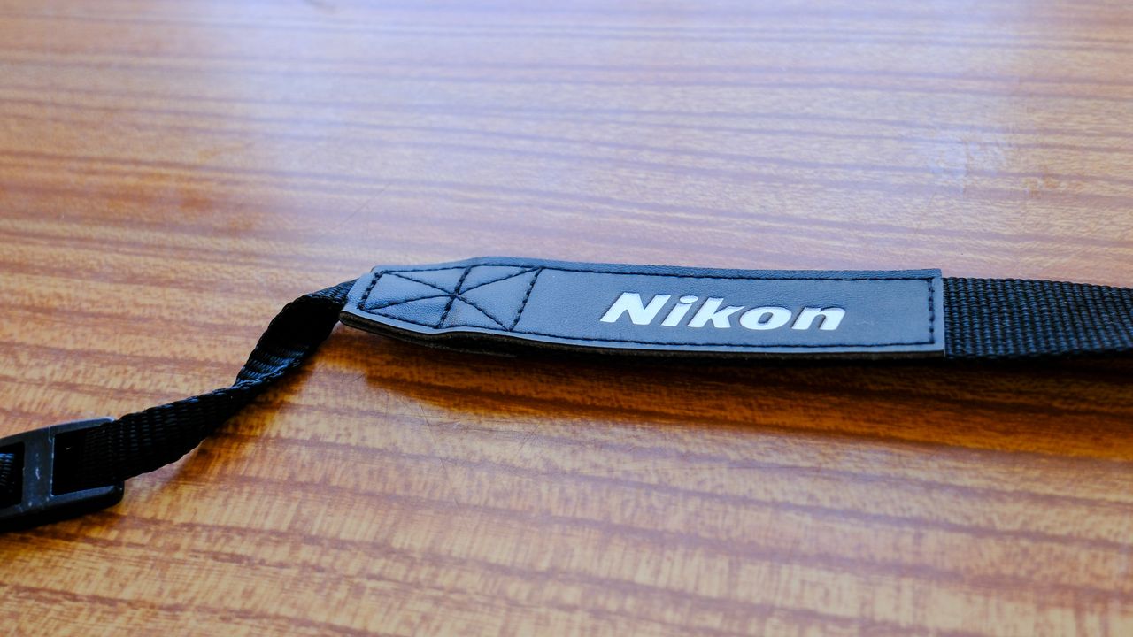 A close-up of the neck strap on the Nikon Action Zoom 10-22x50 binoculars.
