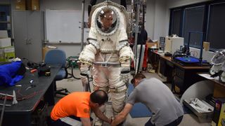 University of North Dakota graduate students Joseph Clift (bottom left) and Bradley Hoffmann (right) help Space.com contributor Elizabeth Howell into the NDX-2 spacesuit. Operations like this one require trust between team members because the person wearing the spacesuit needs help to get in and out of the NDX-2 safely.