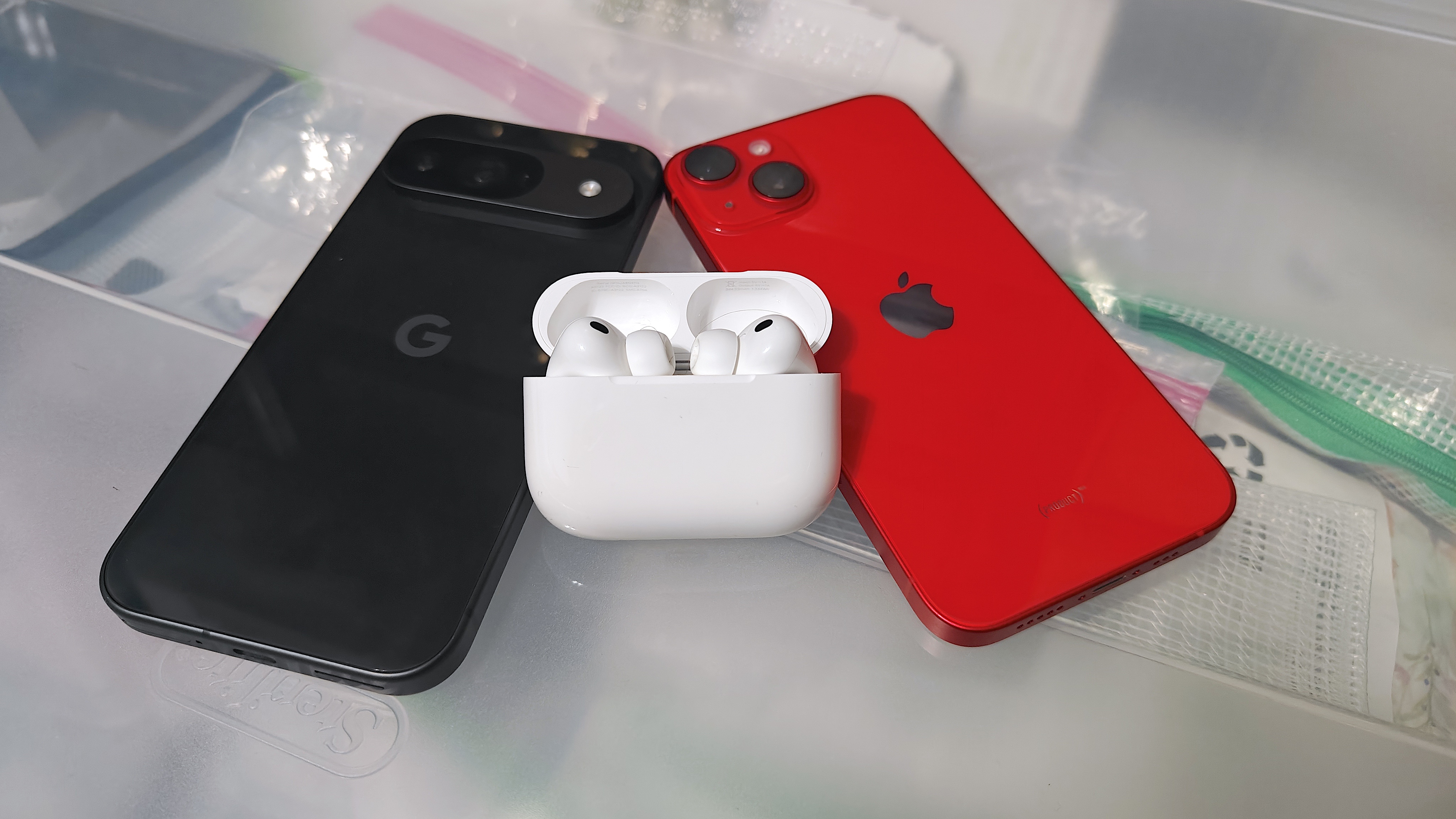 The AirPods Pro 3 propped next to the Google Pixel 9 and iPhone