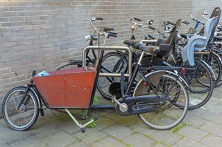 This image shows cargo bikes side on in a line without riders in the background is a brick wall