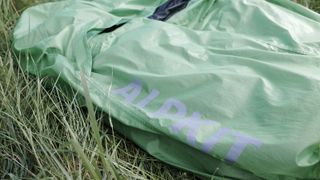 Alpkit Kloke bivy bag lying on grass detailing the logo on the side of the bivy
