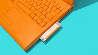 An orange laptop with a floppy disk inserted into it.