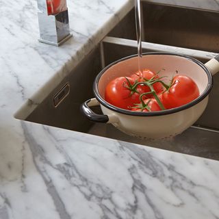 marble worktops kitchen sink and wash tomatoes in white bowl