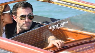 Jennifer Lopez leans in towards Ben Affleck's ear as they ride in a water taxi in Venice.