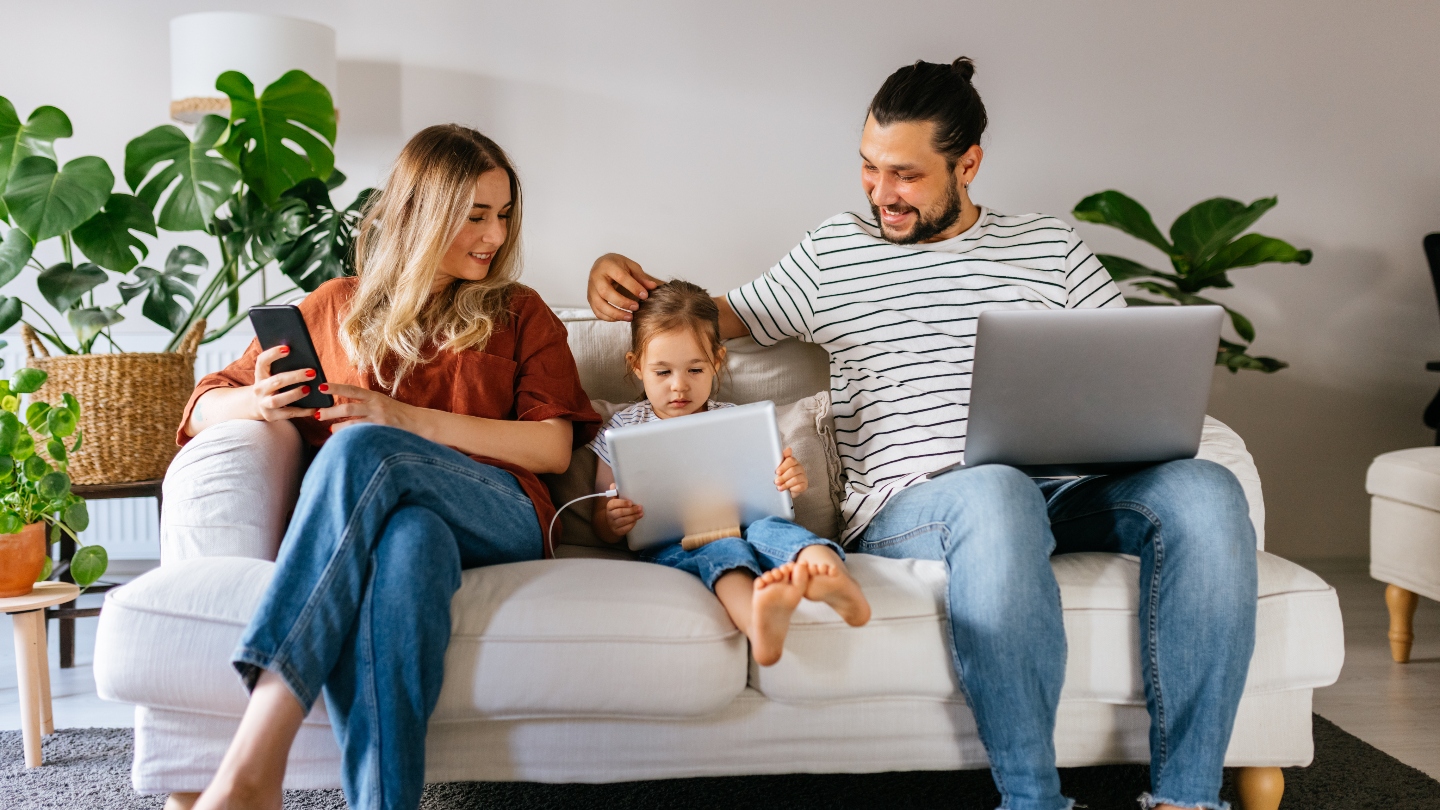 Family sitting on the couch all using technological devices