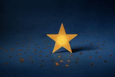 large gold star surrounded by tiny gold stars and dark blue background