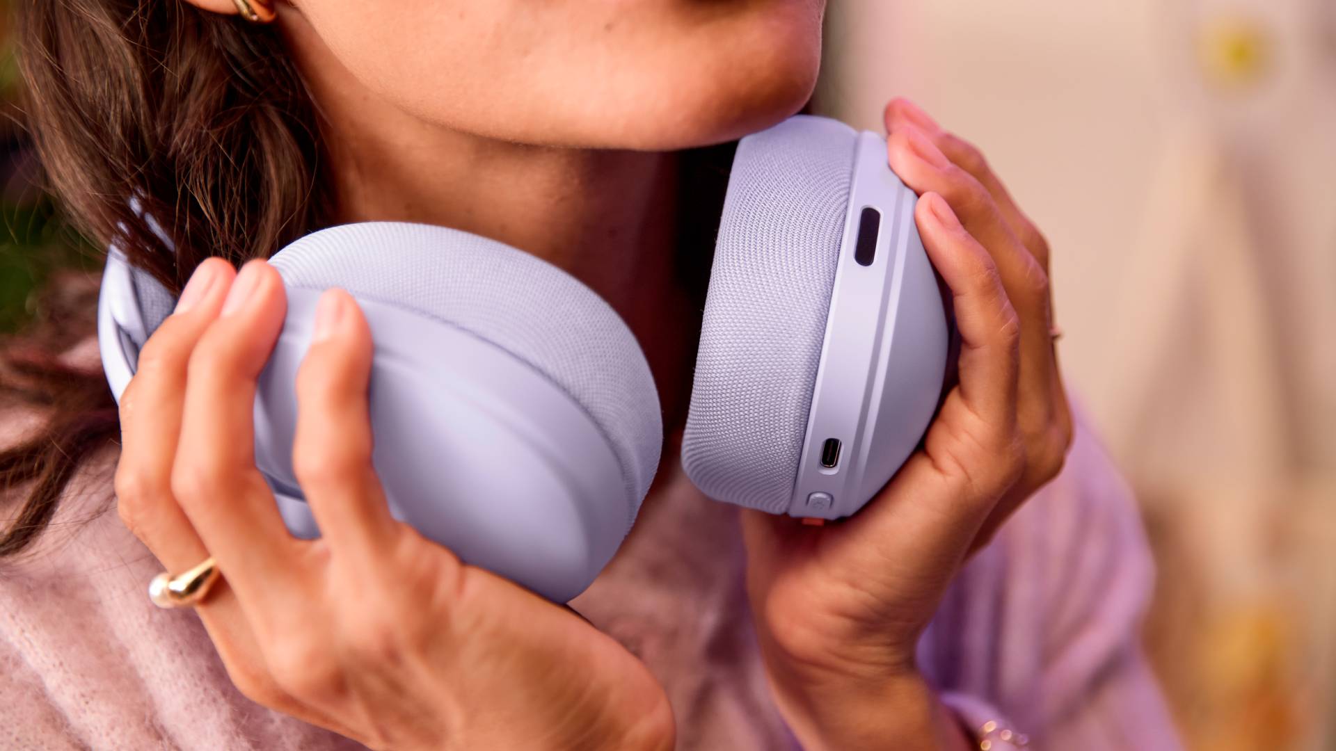 Image of a person holding a lilac Logitech G325 Lightspeed gaming headset.