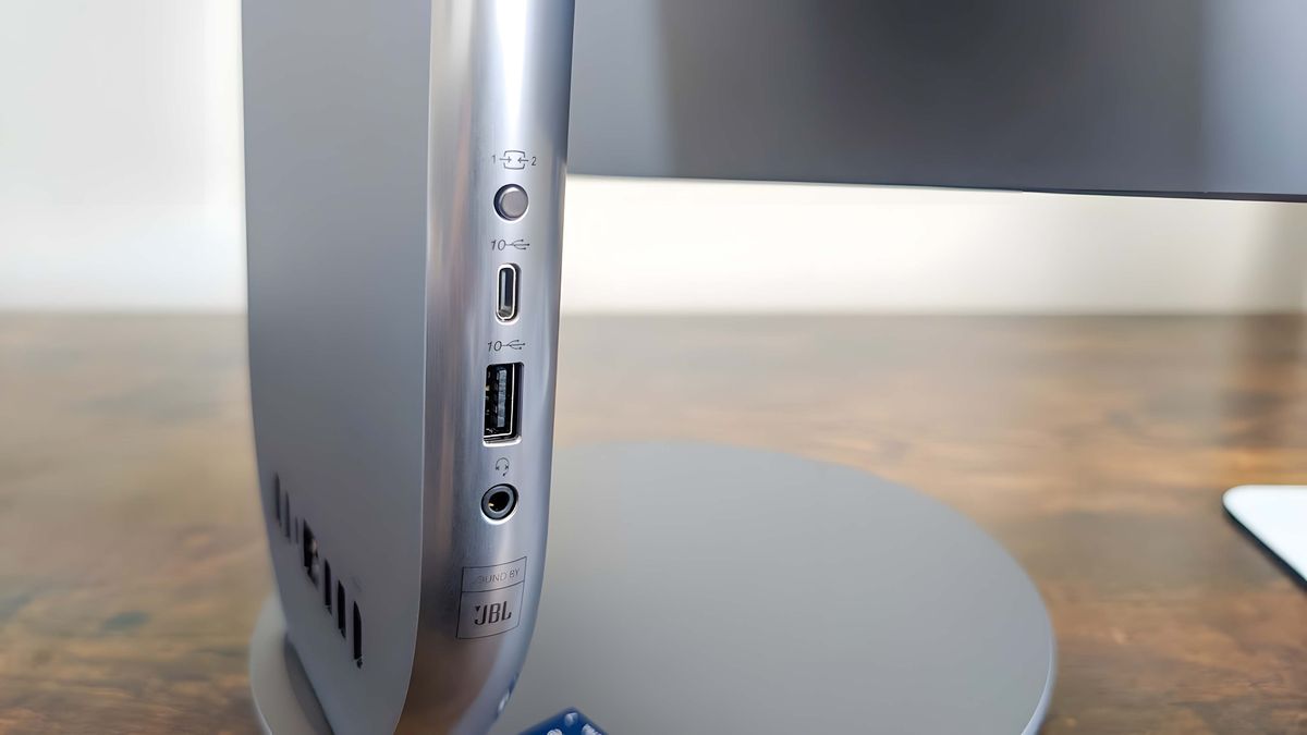 A closeup of the ports and button on the Lenovo Yoga AIO 27" base's right side, which includes a headphone jack, a USB-A port, a USB-C port, and a display button.