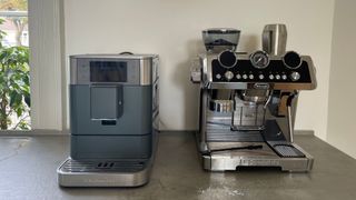 The KitchenAid KF8 Fully Automatic Espresso Machine next to De'Longhi's La Specialista Maestro coffee machine