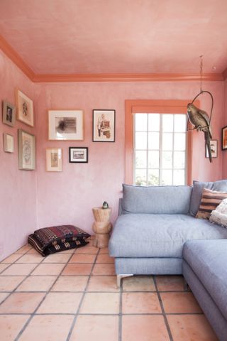 Living room with original faded terracotta floor tiles, pink limewash walls and blue-grey sofa