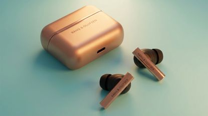 Bang & Olufen Beo Grace Honey Tone earbuds on light green/blue background