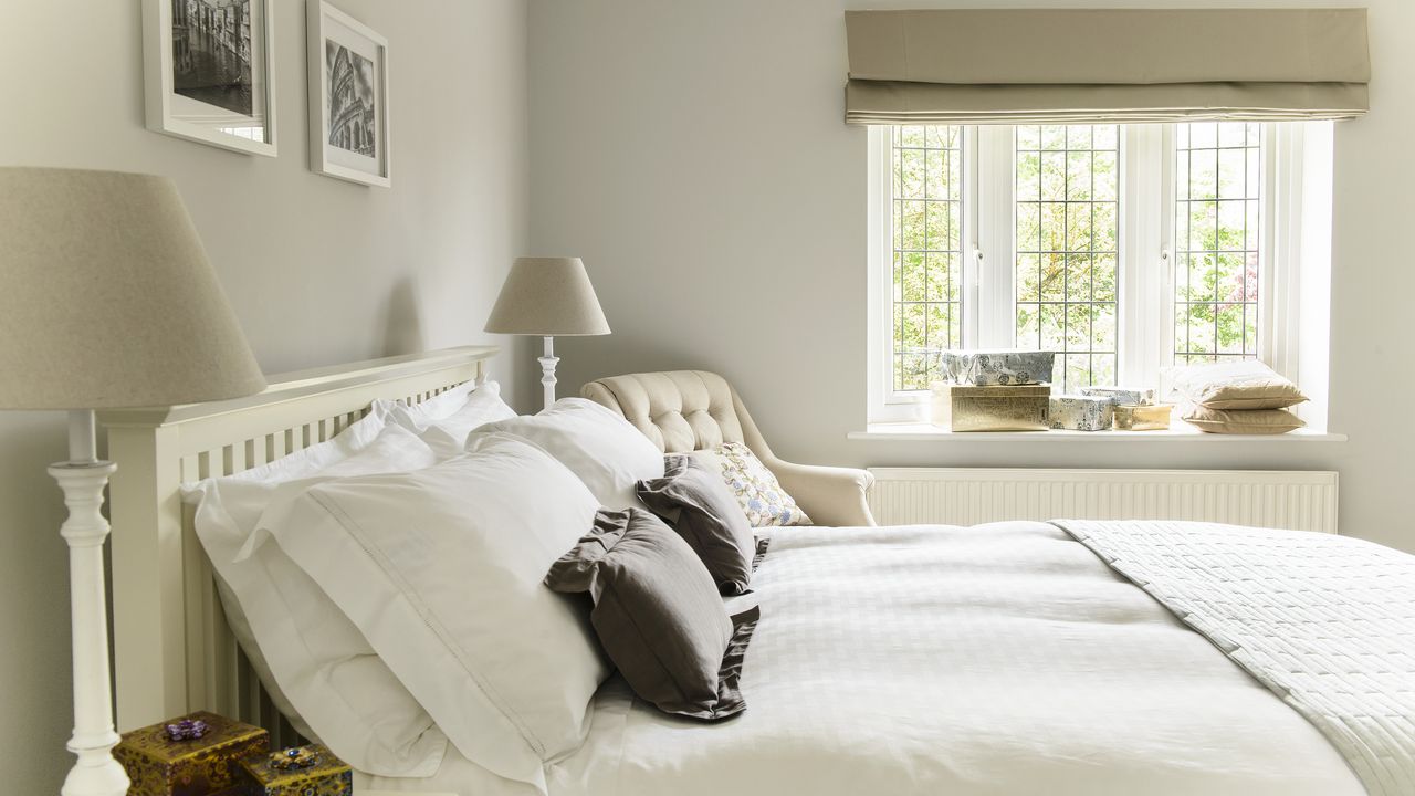 White and cream bedroom with white bedding and lampshades either side of bed.