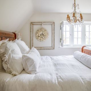 white cottage bedroom with wooden sleigh bed and chandelier